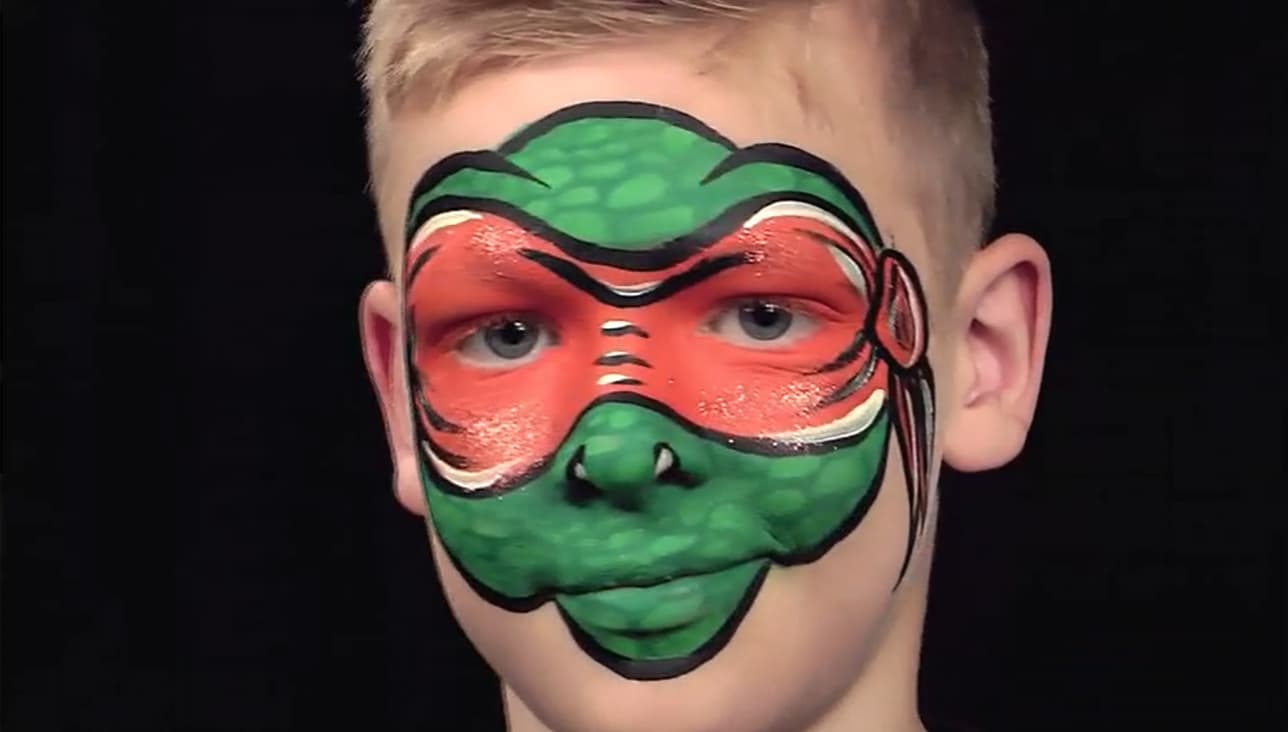 Gutt med grønn og rød sminke i ansiktet. Malt som en karakter fra Ninja Turtle. SKilpadde med rødt bånd over øyne.
